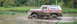 1979 Ford Bronco - A red and white Ford Bronco navigates a muddy path, kicking up water and dirt.