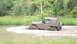 1979 Ford Bronco - A Jeep CJ-8 Scrambler navigates a muddy terrain, kicking up dirt and water.