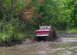 1979 Ford Bronco - Red pickup truck navigates a muddy trail, splashing water and dirt.