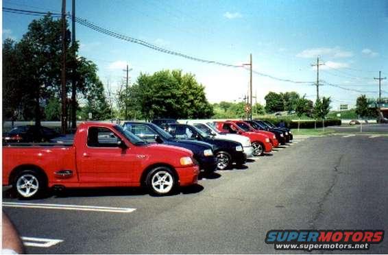 Red pickup truck with a short bed and custom wheels parked in a lot
