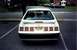 1989 Ford Mustang - The rear of a white 1987 Ford Mustang is visible, parked in a lot with other vehicles.