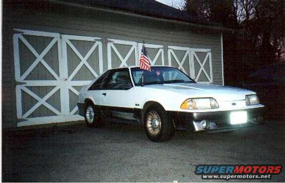 White 1989 Ford Mustang GT parked in front of a garage