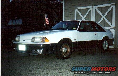 1989 Ford Mustang GT coupe, white over black, parked in front of garage