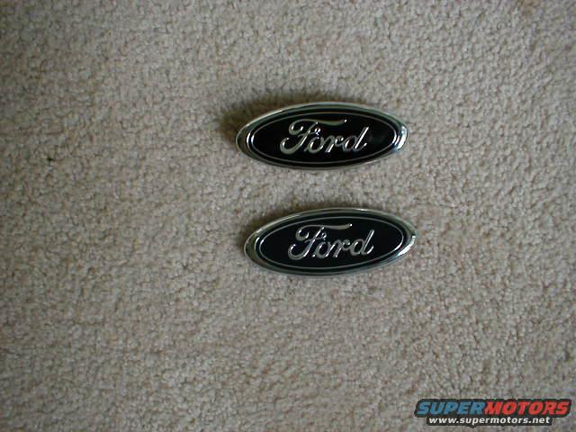 Two Ford oval emblems on a carpeted surface
