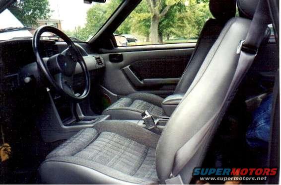 Gray fabric and leather car interior with plaid seats and a black steering wheel