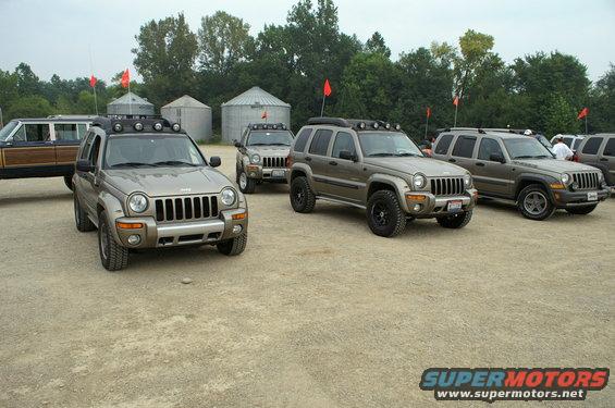 Tan 2006 Jeep Liberty SUVs with roof lights parked in a gravel lot