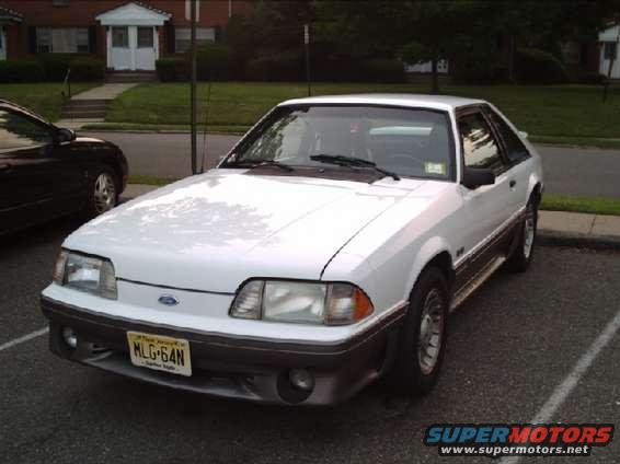 White 1989 Ford Mustang GT parked in a lot. License plate is MLG-64N