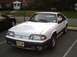 1989 Ford Mustang - A white 1989 Ford Mustang GT is parked in a lot, showing its front 3/4 view and license plate.