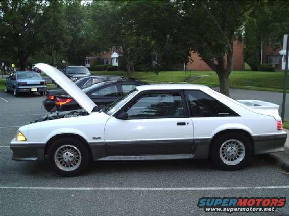 White 1987 Ford Mustang coupe with hood open, parked on asphalt
