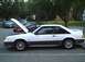 1989 Ford Mustang - A white 1987 Ford Mustang coupe is parked with its hood open, alongside other vehicles.