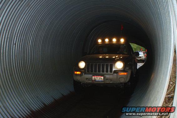 2006 Jeep Liberty with roof lights driving through a metal tunnel, another Jeep visible ahead