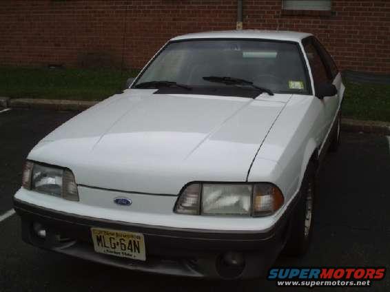 White 1989 Ford Mustang GT parked in front of a brick building