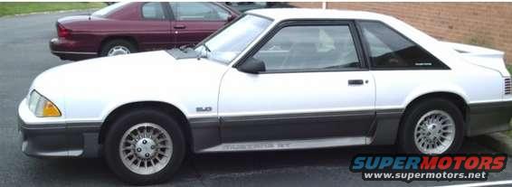 White coupe car with a dark gray lower body trim and a rear spoiler, seen from the side