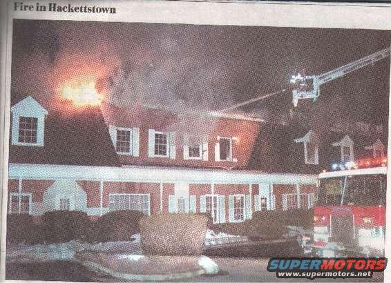 Fire truck at a burning building with smoke and flames, ladder extended