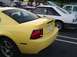1989 Ford Mustang - A yellow Ford Mustang is parked next to other vehicles.