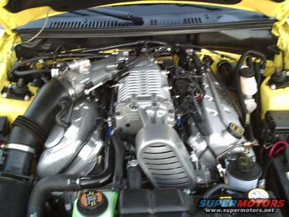 Close-up of a supercharged V8 engine with silver intake manifold and black hoses