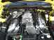 1989 Ford Mustang - The engine bay of a yellow car, showing a prominent supercharger and various engine components.