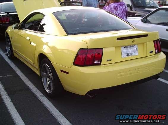 Yellow Ford Mustang with a black spoiler and SVT badging, viewed from the rear