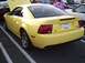 1989 Ford Mustang - A yellow Ford Mustang is parked in a lot, with its hood up and other vehicles nearby.