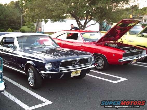 Dark blue convertible Mustang parked next to a red Dodge Charger with hood open