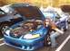 1989 Ford Mustang - A woman poses with a blue convertible that has its hood open, parked next to another vehicle.