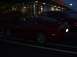 1989 Ford Mustang - A red sports car is parked in a lot at night, with another vehicle visible behind it.