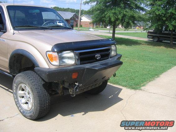 Tan Toyota Tacoma with aftermarket bumper and bug deflector, parked on a driveway