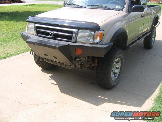 Tan Toyota Tacoma with aftermarket bumper and bug deflector, front 3/4 view