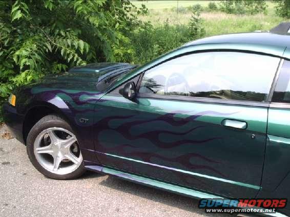 Green Ford Mustang with purple flame decals, side view, showing hood scoop and GT badge