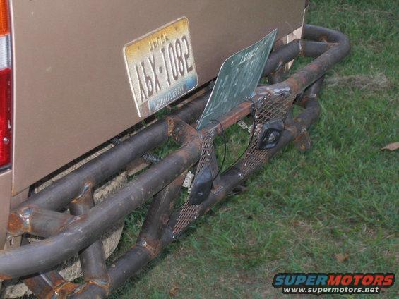 Rear view of a brown truck with a custom metal bumper and license plate ABX-1082