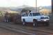 1994 Ford F-150 - A white pickup truck competes in a pulling event, dragging a heavy trailer across a dirt track.