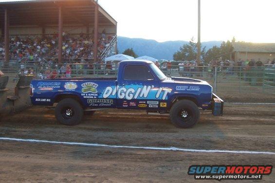 Blue pickup truck with "DIGGIN' IT" text and sponsor decals in a pull competition