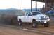 1994 Ford F-150 - A white Dodge Ram pickup truck competes in a truck pull event, dragging a weighted sled across a dirt track.