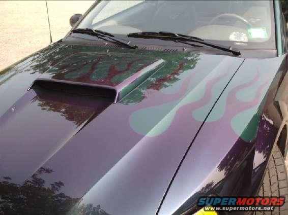 Dark purple Ford Mustang hood with a functional scoop and green and red flame decals. The car is angled from the front