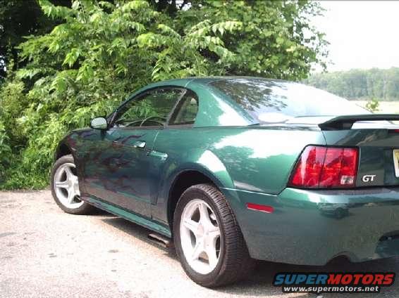 Green Ford Mustang GT parked by some trees