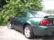 1989 Ford Mustang - The rear quarter panel of a green Ford Mustang GT is visible, with a spoiler and distinctive taillights.
