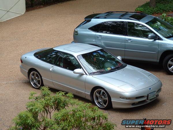 Silver 1993 Ford Probe with aftermarket wheels parked next to a silver SUV