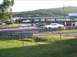 1989 Ford Mustang - A white coupe is seen on the drag strip at Island Dragway, with other vehicles and spectators in the background.