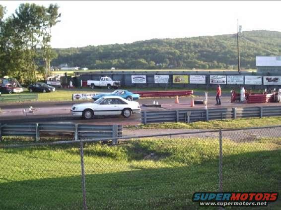 1989 Ford Mustang on drag strip with other cars and a truck in background