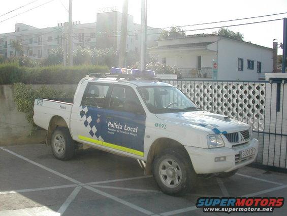 White police pickup truck with blue and yellow markings, parked in a lot