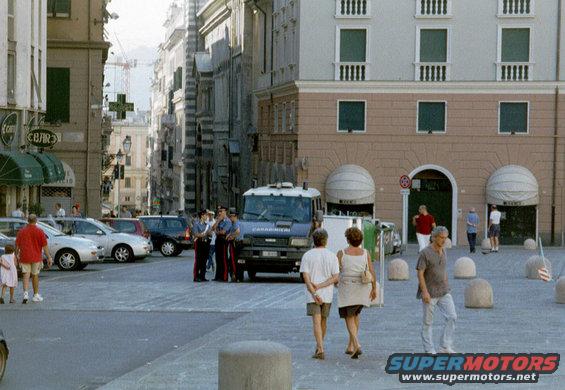 Italian police van parked in a square with other cars and people walking around