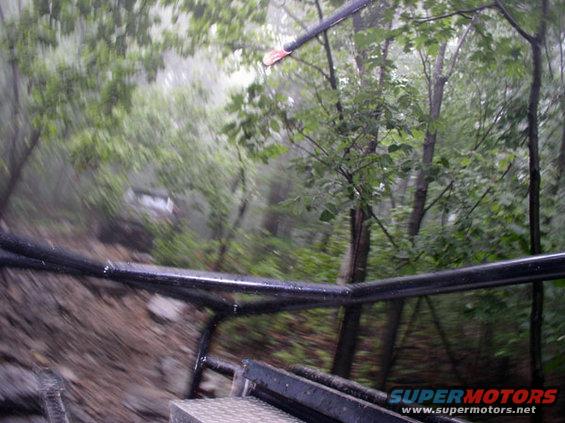 White SUV on a muddy forest road, viewed from inside another vehicle