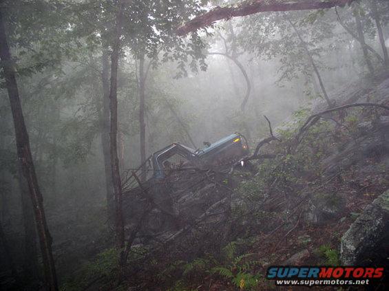 1988 Ford Bronco stuck on a rocky, wooded slope in fog