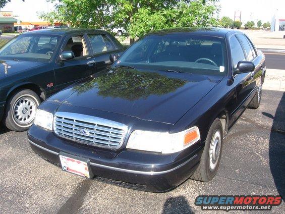 Black Ford Crown Victoria parked next to another car. Front grille and headlights visible