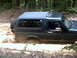 1996 Ford Bronco - Ford Bronco navigating a muddy off-road path surrounded by trees.