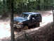 1996 Ford Bronco - A dark green 1992 Ford Bronco navigates a muddy off-road trail.