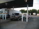 1995 Ford C-350 (Centurion Conversions) - A dark green SUV with a trailer is parked at a gas station, with several semi-trucks visible in the background.