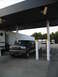 1995 Ford C-350 (Centurion Conversions) - A dark blue 1995 Ford C-350 Centurion Conversions SUV is parked at a gas station, towing a small trailer.