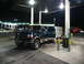 1995 Ford C-350 (Centurion Conversions) - A Ford F-Series truck is parked at a gas station with its door open and a trailer attached.