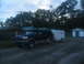 1995 Ford C-350 (Centurion Conversions) - A dark blue Ford Bronco is parked next to a white trailer.